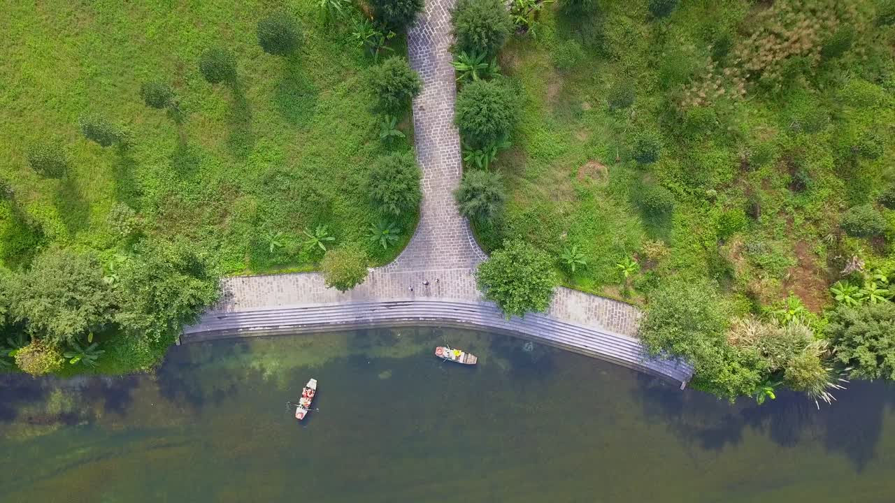 Cinematic drone footage of majestic green limestone peaks. Ricefields in the wild jungle in the spring with boat tour canal in Trang An, Ninh Binh, Vietnam