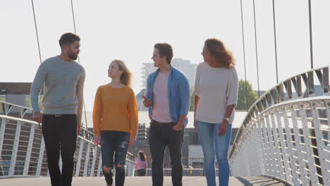 group of young friends walking over city bridge together