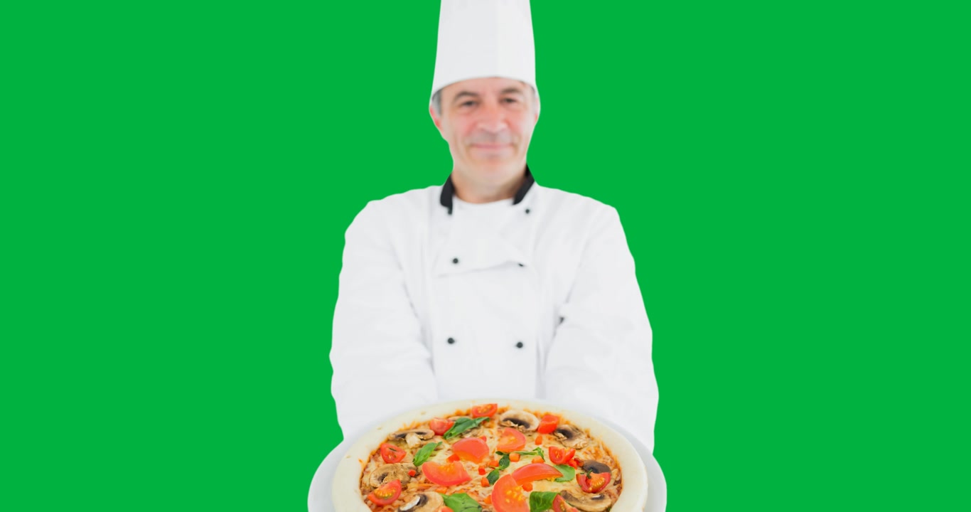 Portrait of caucasian male chef holding a pizza plate against black background