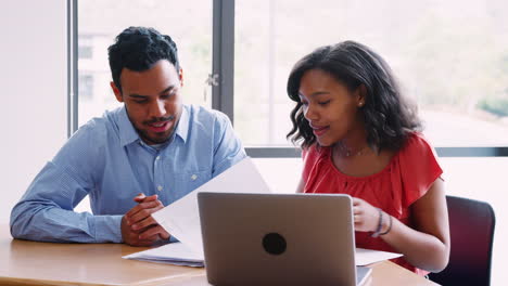 High-School-Tutor-Giving-Female-Student-One-To-One-Tuition-At-Desk