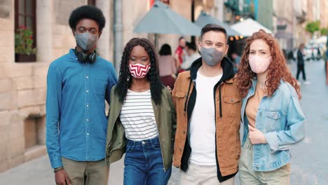 group of multiethnic friends wearing mask and looking at the camera in the street