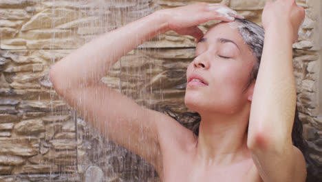 Biracial-woman-relaxing-and-taking-shower-in-bathroom