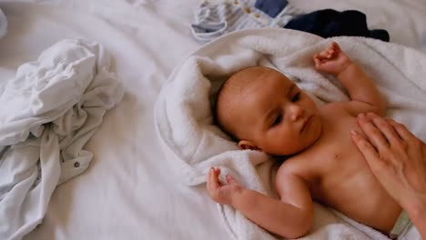 un bebé lindo recibiendo un masaje de su madre en la cama 4k