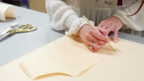 la hermosa diseñadora de moda dibuja en las plantillas de papel para cortar tela en los maniquíes vestidos con vestidos de novia. fabricante de vestidos de novia.