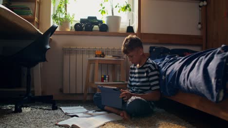 boy studying on a tablet in his bedroom