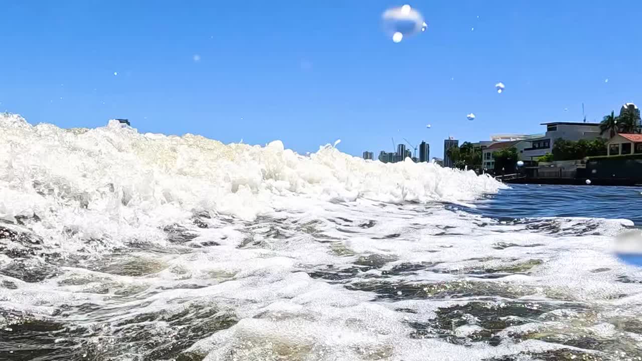 Experience the power and motion of ocean waves crashing near the shore under a clear blue sky.