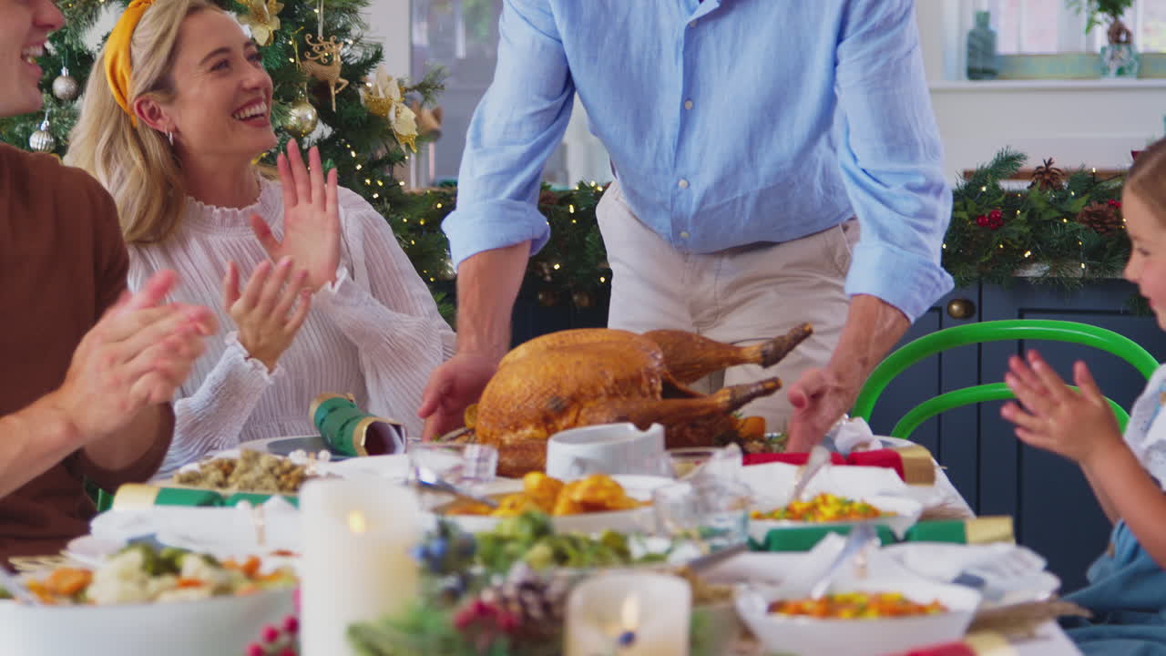 familia de varias generaciones celebrando navidad en casa con el abuelo sirviendo pavo