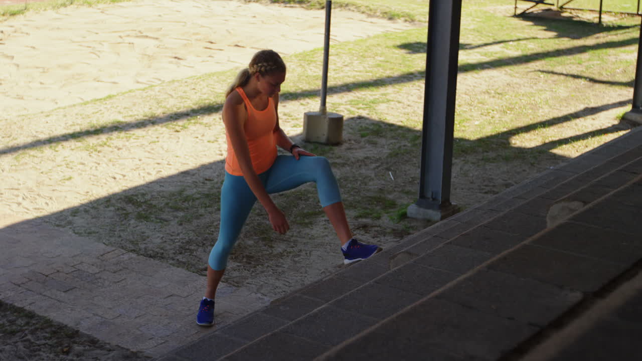 vista lateral de una atleta caucásica haciendo ejercicio en las escaleras de un recinto deportivo 4k