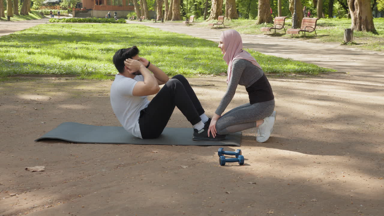 hombre y mujer haciendo abdominales en el parque