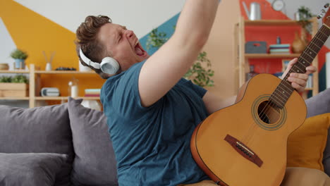 man singing along to music while playing guitar on a couch