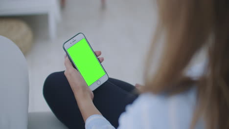 Mujer-Usando-Y-Mirando-La-Pantalla-Verde-Del-Teléfono-Inteligente-En-Casa.-La-Joven-Sostiene-Un-Teléfono-Inteligente-Con-Pantalla-Verde-Por-La-Noche.