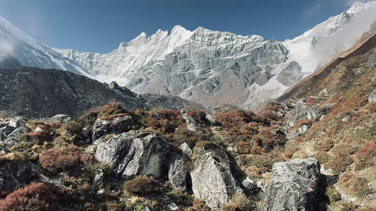Rugged Himalayan terrain near Tilicho Lake in the Annapurna region of Nepal, with rocky slopes, alpine vegetation, and snow-capped peaks under a clear sky creating a dramatic mountain scene