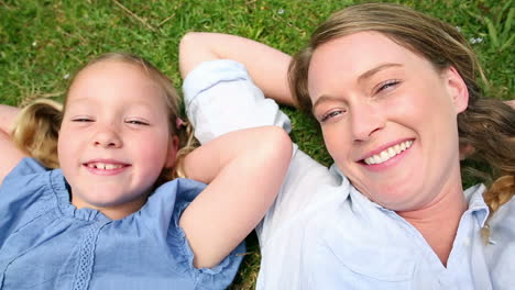 madre feliz acostada en la hierba con su niña en el parque