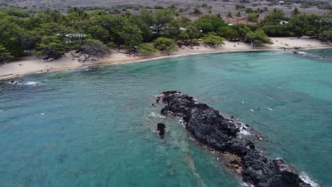 cinematic clockwise drone shot of a lava island formed in the water at waialea beach on the big island of hawaii