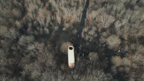 ascending drone view of an abandoned cooling pipe from the soviet union era in the middle of a forest