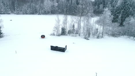 Toma-Aérea-Ascendente-De-Una-Casa-Aislada-Rodeada-De-Bosques-Cubiertos-De-Nieve-En-Letonia