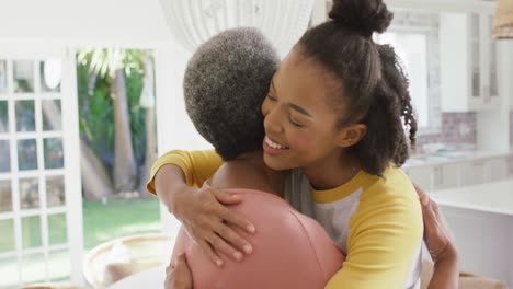 african american mother and daughter hugging each other in the living room at home