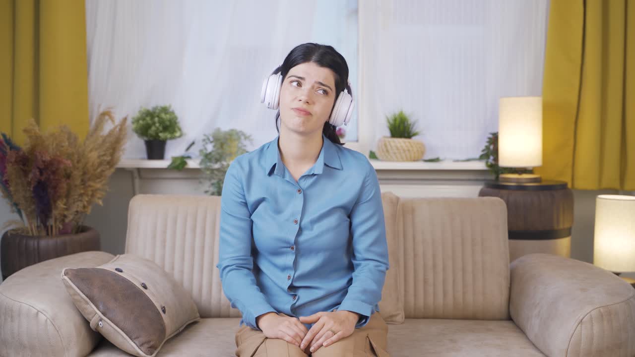 헤드폰으로 음악을 듣는 젊은 여성은 불행하고 슬프다.