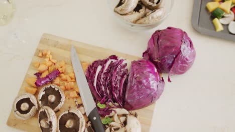 Over-head-view-of-fresh-vegetables-on-chopping-board-and-baking-tray-on-kitchen-counter-top