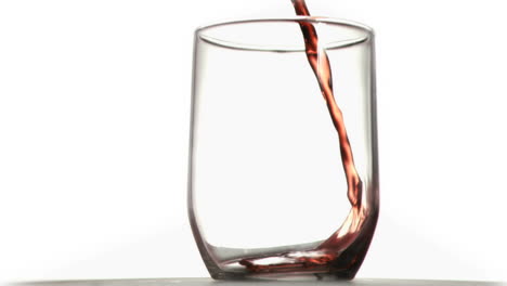 Red-thin-trickle-in-a-super-slow-motion-falling-in-a-glass-