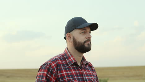 close up of the handsome farmer in a hat walking in the field