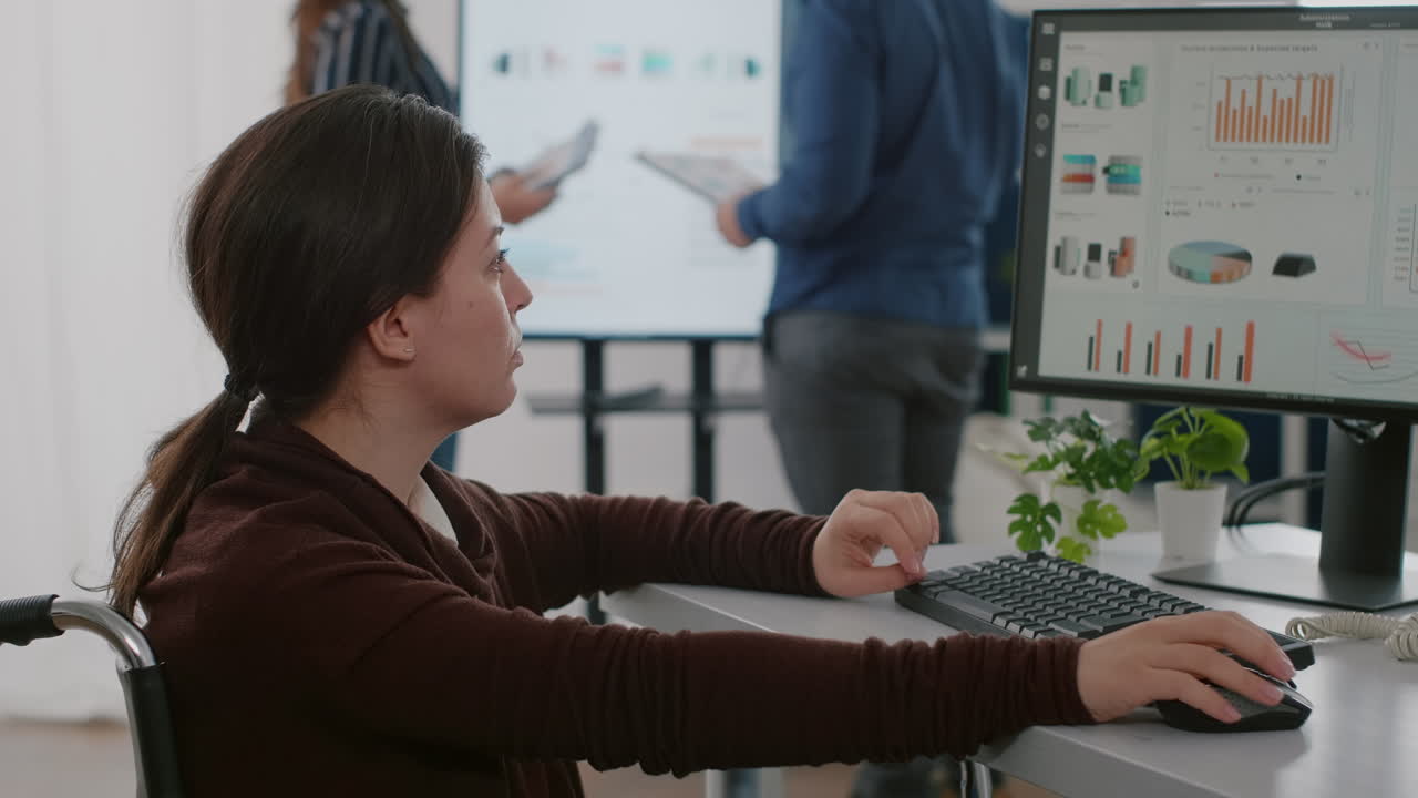 Invalid financial expert sitting in wheelchair working in busy start up company