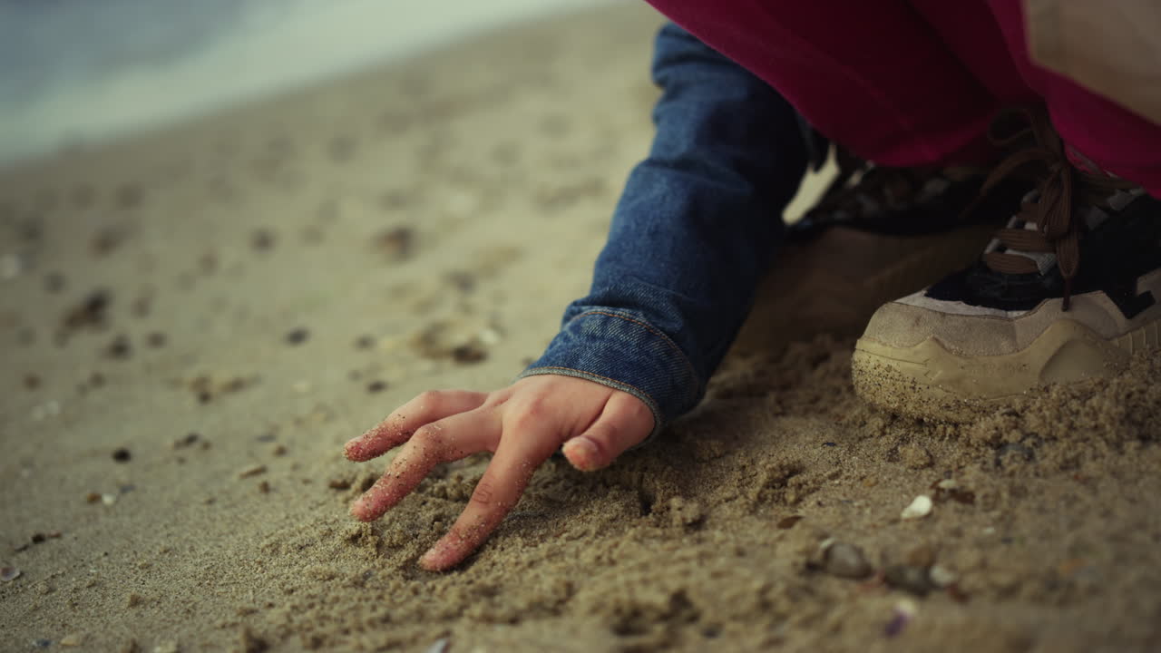 어린이 손이 모래를 그리고 있습니다. 어린 소녀 아이는 바다 해변에서 야외 자연을 즐기고 있습니다.