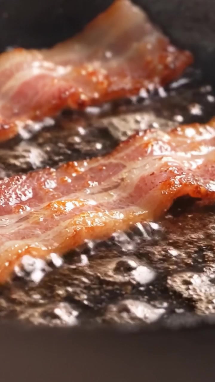 Pancetta sfrigolante in padella: Una delizia croccante e appetitosa catturata mentre cuoce alla perfezione, che emana un aroma delizioso e un'essenza saporita