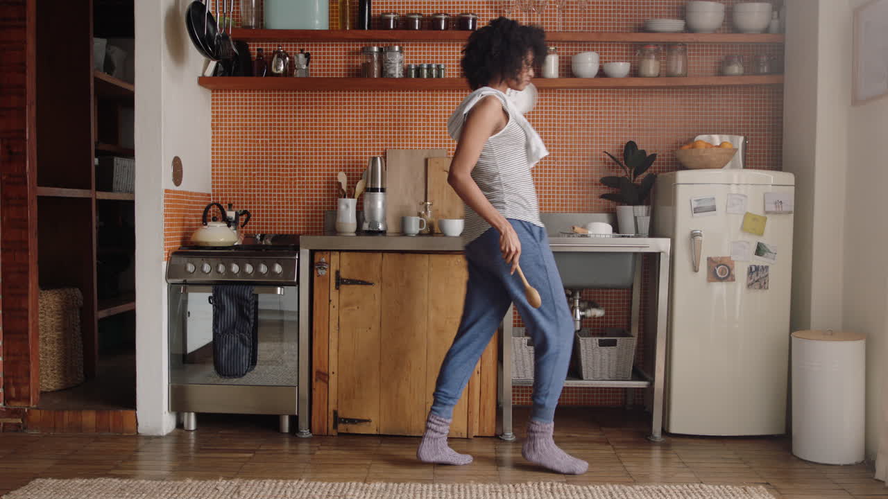 donna felice che balla in cucina celebrando uno stile di vita di successo godendo di una gioiosa celebrazione della danza della vittoria