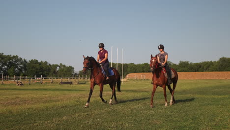 two women riding horses in a field