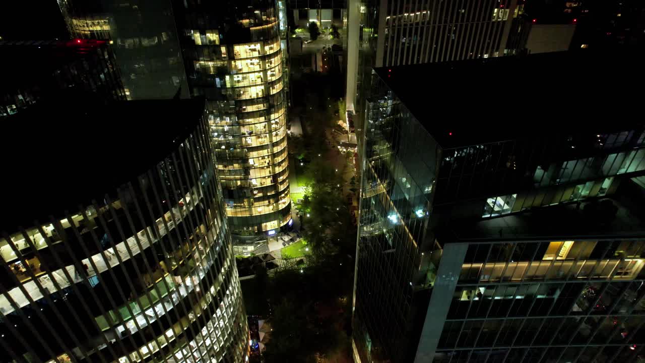 drone volando en medio de coloridos condominios iluminados por la noche, en las condes, chile