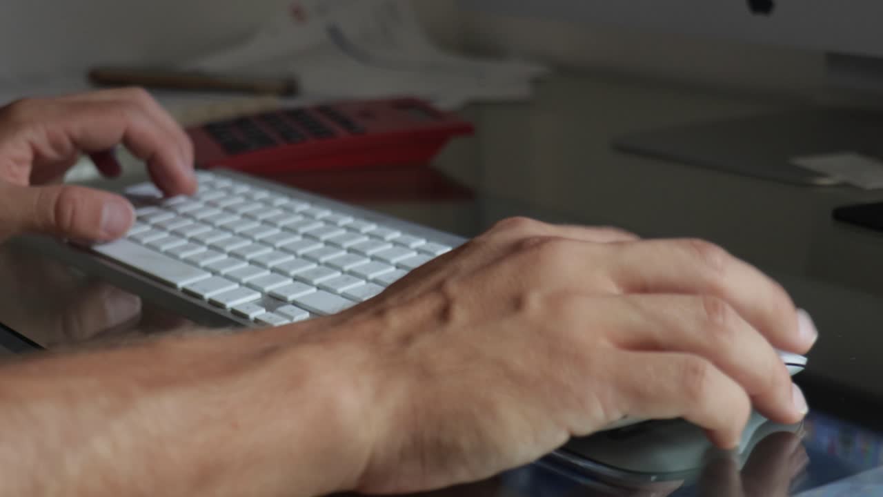블루투스 키보드에 입력하고 유리 테이블 위로 마우스를 드래그하는 남성 손 근접 촬영