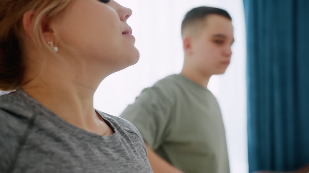 Primer plano de entrenador y estudiante levantando los brazos durante una sesión de estiramientos laterales en interiores, centrándose en la alineación de la postura, la concentración y el entrenamiento de flexibilidad para ganar fuerza.