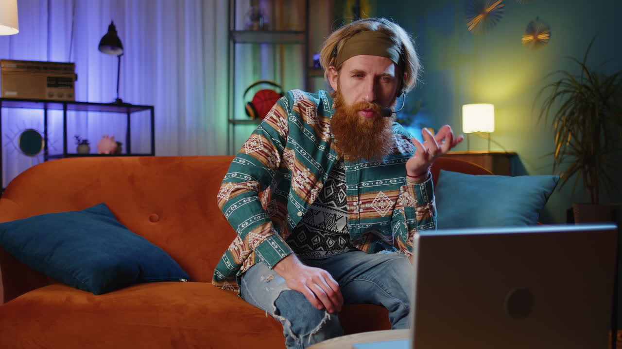 hombre con barba en un sofá hablando en un auricular