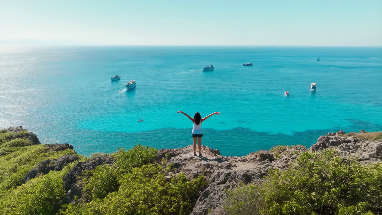 Woman with arms raised overlooking a vast blue ocean with boats