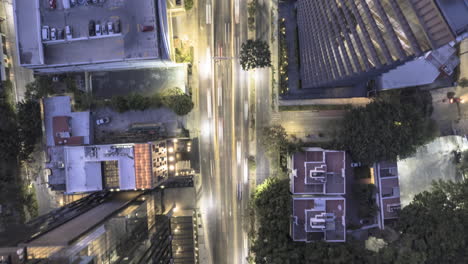 cenital hyperlapse of a moderately busy avenue with vehicles, surrounded by tall buildings, showcasing a spectacular perspective of their height