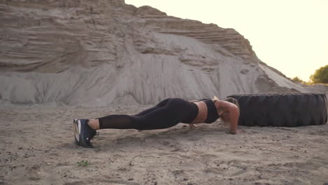 girl coaches outdoors jumping burpee through the wheel. workout crossfit workout. setting sun