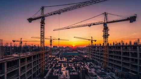 construction cranes and buildings at sunset