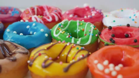 lush appetizing donuts are covered with bright multi-colored glaze. on top of the glaze, colored sprinkles and dark and white chocolate. sweets close-up. obesity concept