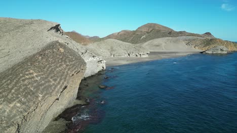 Volcanic-Cliffs-at-Monsul-Beach,-Cabo-de-Gata,-Almeria,-Andalusia,-Spain---Aerial-4k