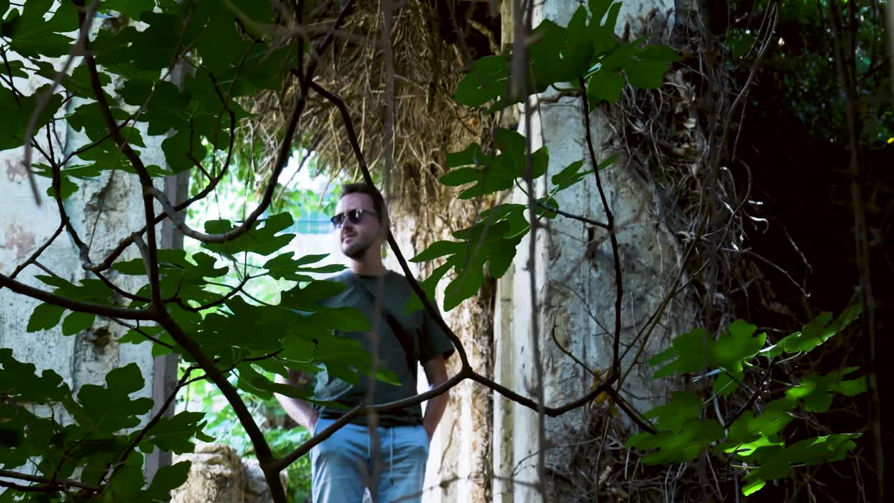 Man Exploring Abandoned Building in a Green Garden