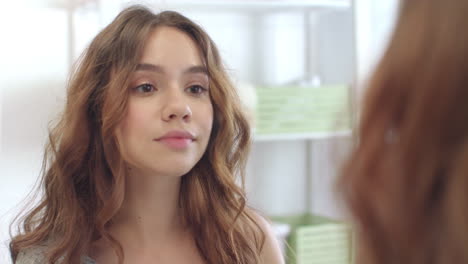 smiling woman using care cream in bathroom. woman applying cosmetic cream