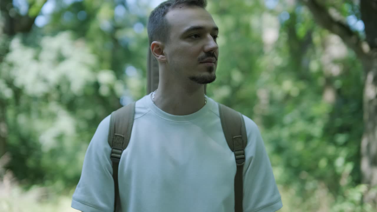joven caminando con la guitarra en la calle cerca del bosque