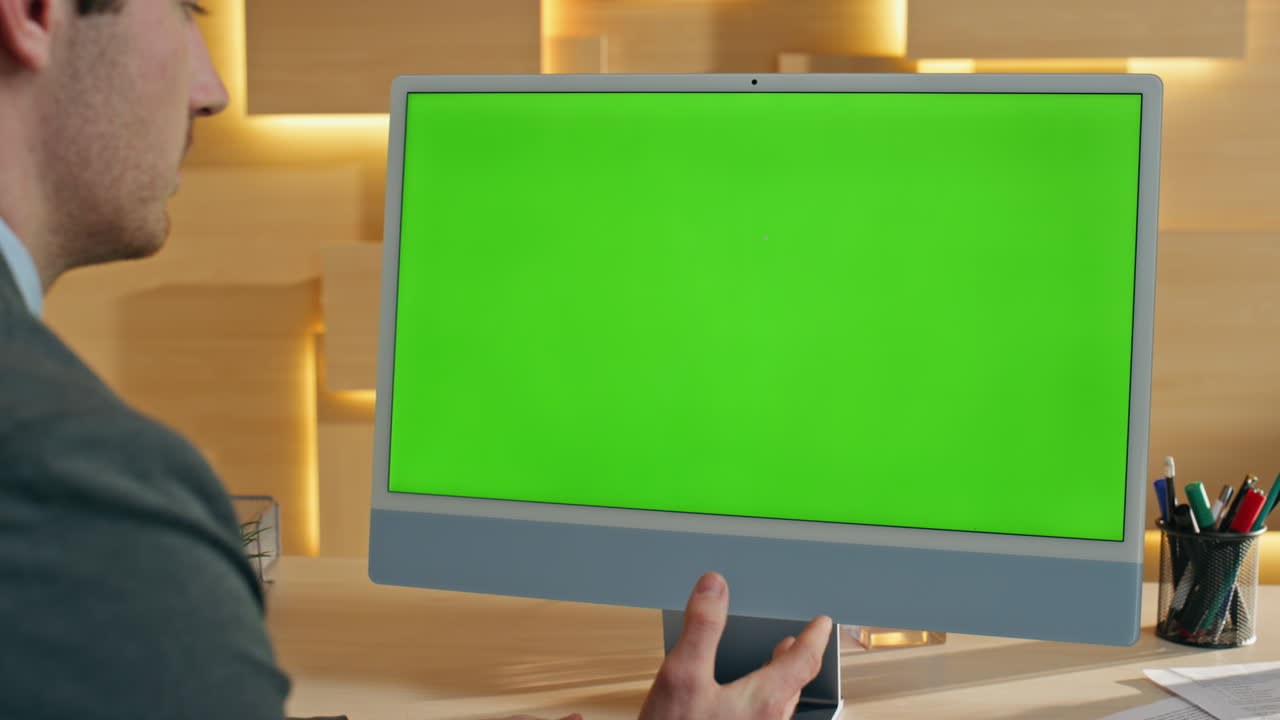 Businessman looking at a computer with a green screen