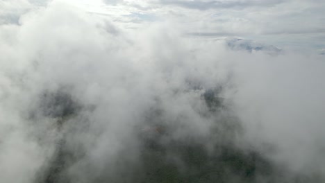 jib down with drone above clouds and forest at a foggy morning in colombia