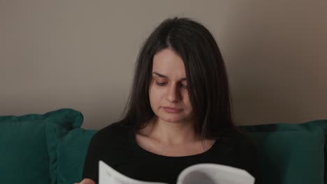 a young woman seated on the couch, engrossed in reading a book - close up