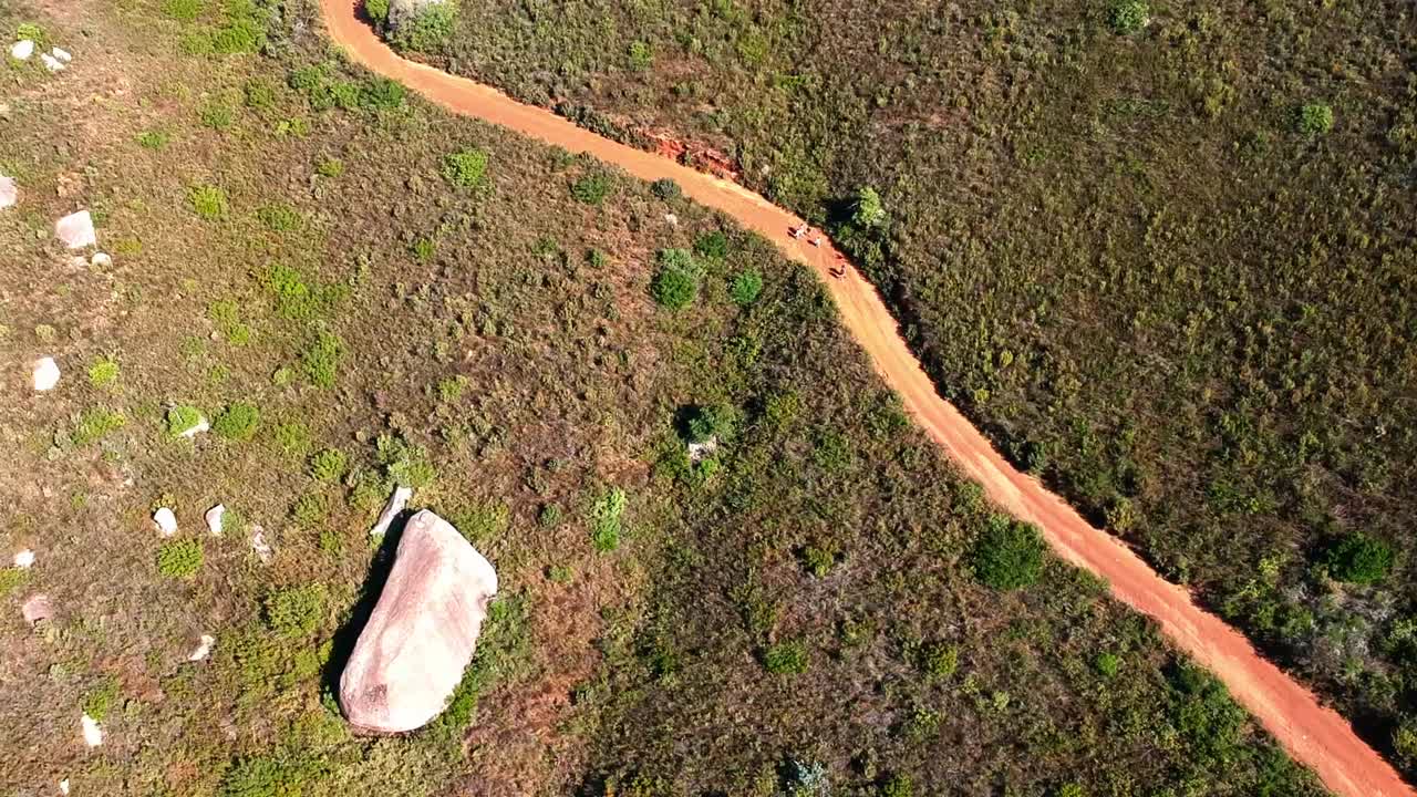 una vista de avión no tripulado de personas caminando por un camino de tierra en el lado de una colina empinada