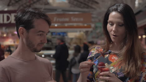 a couple tasting fruits on a local market