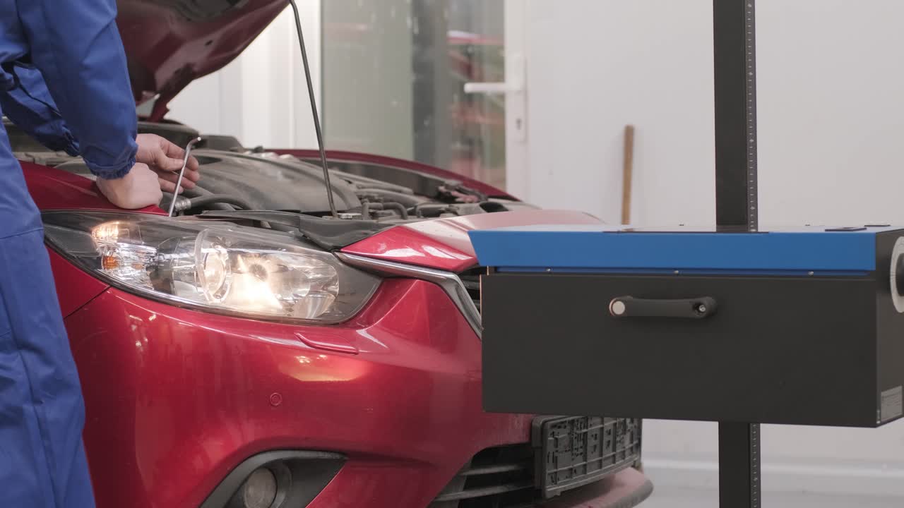 노동자는 자동차 조명 시스템의 헤드라이트를 확인하고 조정합니다.