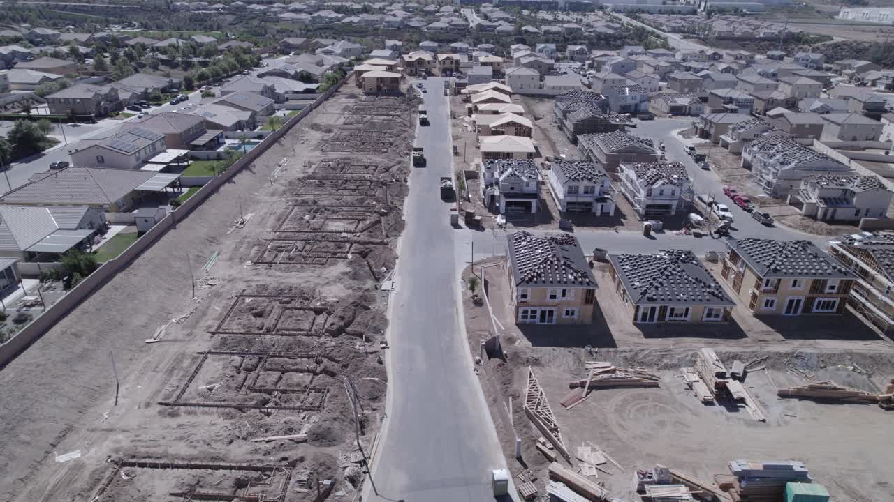 un drone de alta visión captura un sitio de construcción de viviendas, revelando la transformación de lotes desnudos a lotes con personas mudadas, mostrando el progreso dinámico del desarrollo residencial